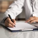 close-up of a doctor writing medical notes and completing paperwork