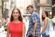 man walking with his girlfriend looking with amazement at another attractive woman passing by
