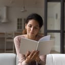 A woman sitting on a couch, reading a book