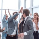 Two coworkers congratulating each other in an office full of applauding businesspeople