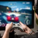 Man playing a racing video game in front of a large screen TV.