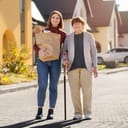A young woman assisting her grandma with carrying groceries while they walk back home from the shop.