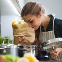 young woman in apron cooking at the stove