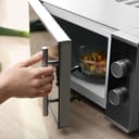 person holding microwave door handle open