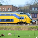 a yellow train passing next to the houses