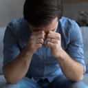 close-up of a distressed young man experiencing an emotional turmoil while sitting on a couch