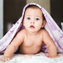 A baby pushed up on its hands under a blanket