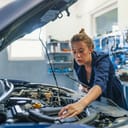 Female mechanic working under the hood of a car