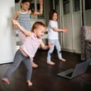Three kids dancing indoors in front of a laptop
