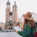 Young female redhead tourist exploring Krakow with a paper map, St. Mary's Basilica in the vicinity
