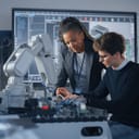 A male engineering student consulting with his female teacher as he works on a computer processor.