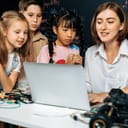 young female teacher coding to show children how to program robots in a STEM class