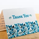 White thank you card with blue letters with note written by hand