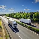 Two cargo trucks driving on the high way in opposite directions.