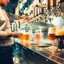 A bartender pouring a large lager beer on tap