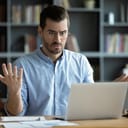 Confused man sitting in front of a laptop