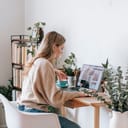 Woman working on laptop at table inside a home environment