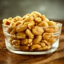 Glass bowl of fresh roasted salted peanuts on an old wooden table