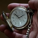 close-up of an open silver and gold pocket watch in a person's hand