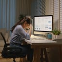 exhausted young woman sitting at her home office desk late into the night, feeling stressed about job challenges
