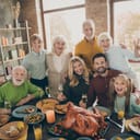 A big family standing and hugging at a feast table.