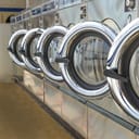 A laundromat with a lot of laundry machines lined up