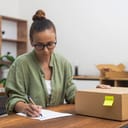 A woman seated at her table, deeply focused on penning a return request.