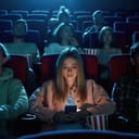young blonde woman texting while at the cinema