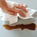 A person wiping a spill using a paper towel