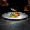 A chef adding sauce over a meal