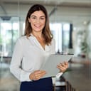 Happy Latin businesswoman and leader standing in the office with a clipboard