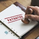 A person stamping a "Patented" stamp on a document