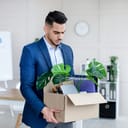 A man holding a boxful of his personal belongings getting ready to exit the premises