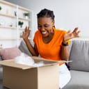 Overjoyed woman unboxing a carton parcel.