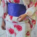 A vibrantly colored traditional Japanese kimono featuring red and pink flowers with a purple obi (belt).