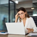 businesswoman with glasses feeling stressed and fatigued, annoyed with her laptop not working properly