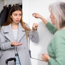 Dissatisfied old woman, owner of apartment, receiving keys from married couple tenants