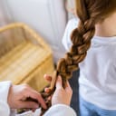 close-up of a mum braiding her young daughter's long hair