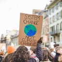 climate change demonstrators with a banner, focus on the banner that says 'System change, not climate change'