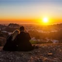 A couple watching sunset on top of a hill