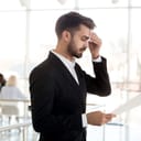 A nervous businessman wiping sweat off of his forehead