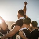 Rugby players lifting the teammate after winning the game. Rugby team celebrating the victory.