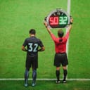 Assistant referee announcing a substitution with a board with the substitute ready to enter the game