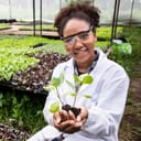 young female scientist holding butterhead lettuce in her hands in an organic farm setting