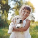 Little girl holding a Golden Retriever puppy in her arms