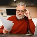 A worried middle aged man looking at paper documents