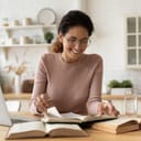 A woman sitting at desk skimming through a book