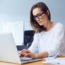 A serious young woman working on her laptop in an office