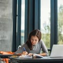 A young female student writing in a notebook in a school library