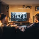 A couple sitting on a couch in the living room watching a movie